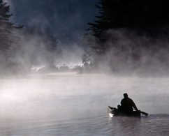 Photograph of a man rowing a boat down a river